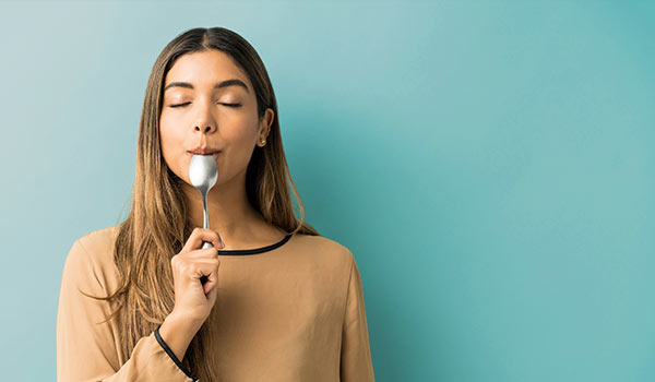 A woman tasting a spoon.