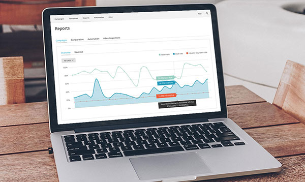 Laptop on a table with email analytics graphs on the screen.