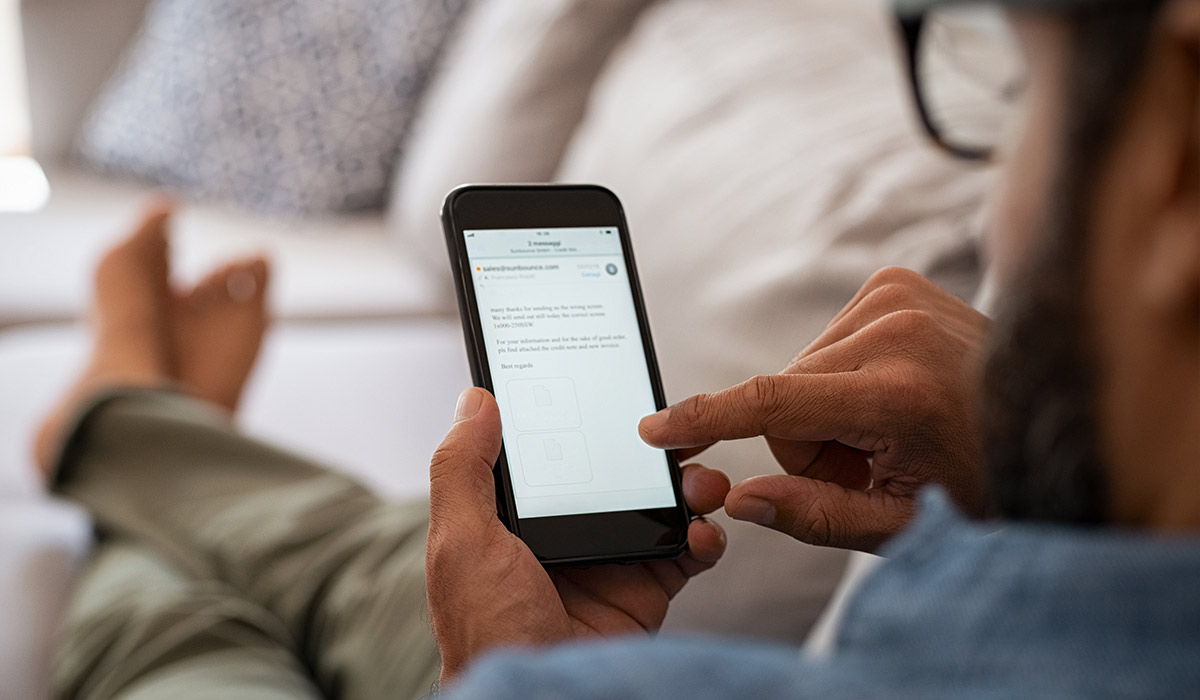 Man on couch reading an email on his phone.