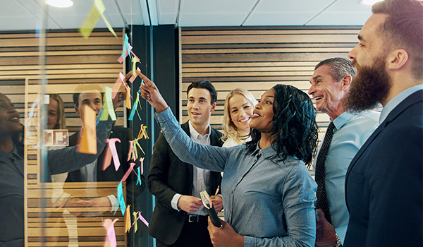 Marketers arranging post-it notes on a glass wall.