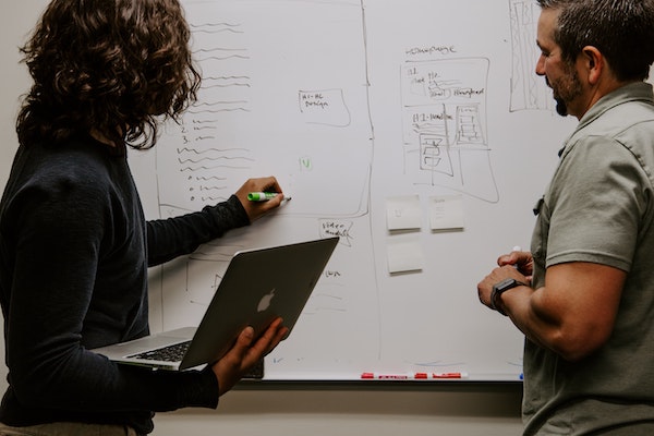 A man and woman plan an email strategy on a whiteboard.