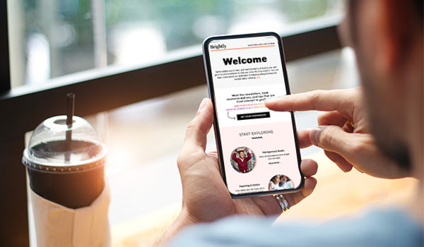 Man with coffee reads welcome email on a smart phone.