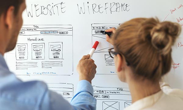 Web designers sketch out wireframe on a whiteboard.