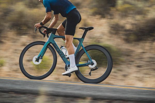 Cyclist riding a blue Giant road bike up a hill.